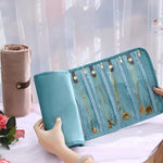 Borsa organizer arrotolabile in velluto per gioielli, con scomparti multipli per collane, bracciali e accessori in oro.